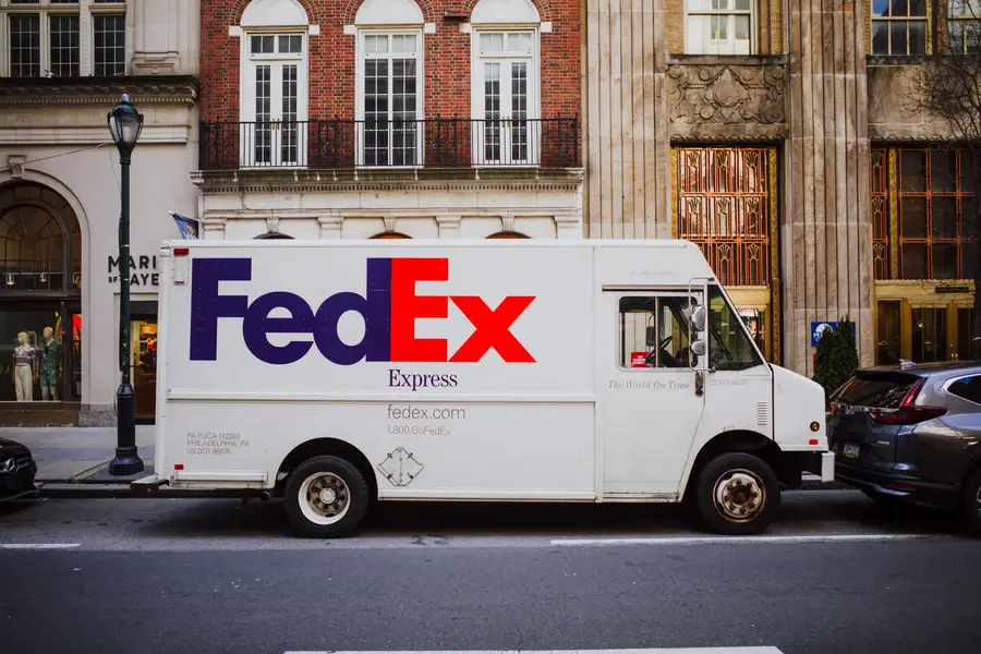 Camion de livraison FedEx Express garé dans une rue, logo violet et orange sur la caisse