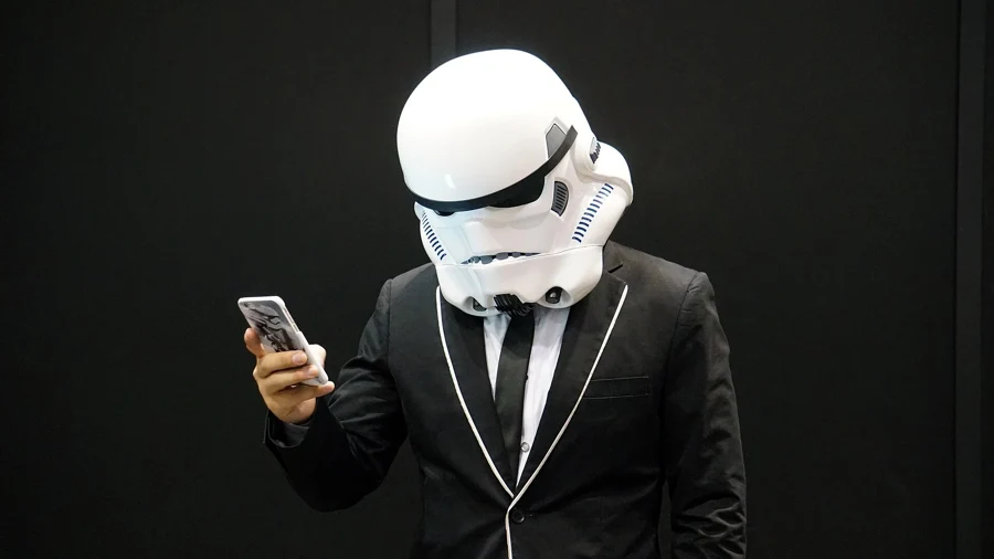 Cosplayer en costume noir et casque de stormtrooper consultant son t&eacute;l&eacute;phone